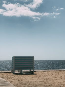 A peaceful beach scene with a changing cabin by the sea and a clear sky.