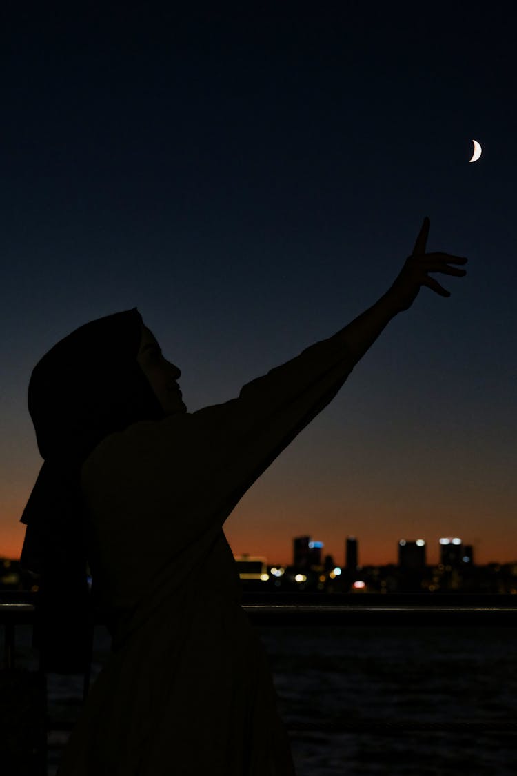 Silhouette Of A Woman Reaching For The Moon