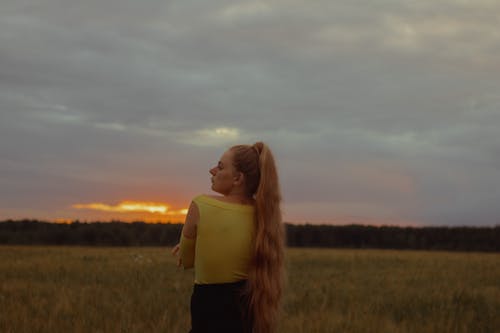 Woman in Yellow Top Standing on Green Grass Field