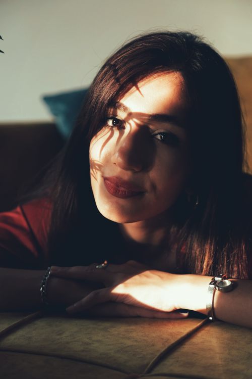 Free A captivating portrait of a smiling woman with artistic shadows on her face, exuding warmth. Stock Photo
