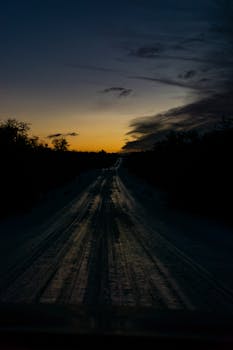Capture of a serene sunset over a dirt road in Tolhuin, Argentina, exuding a warm, tranquil mood.