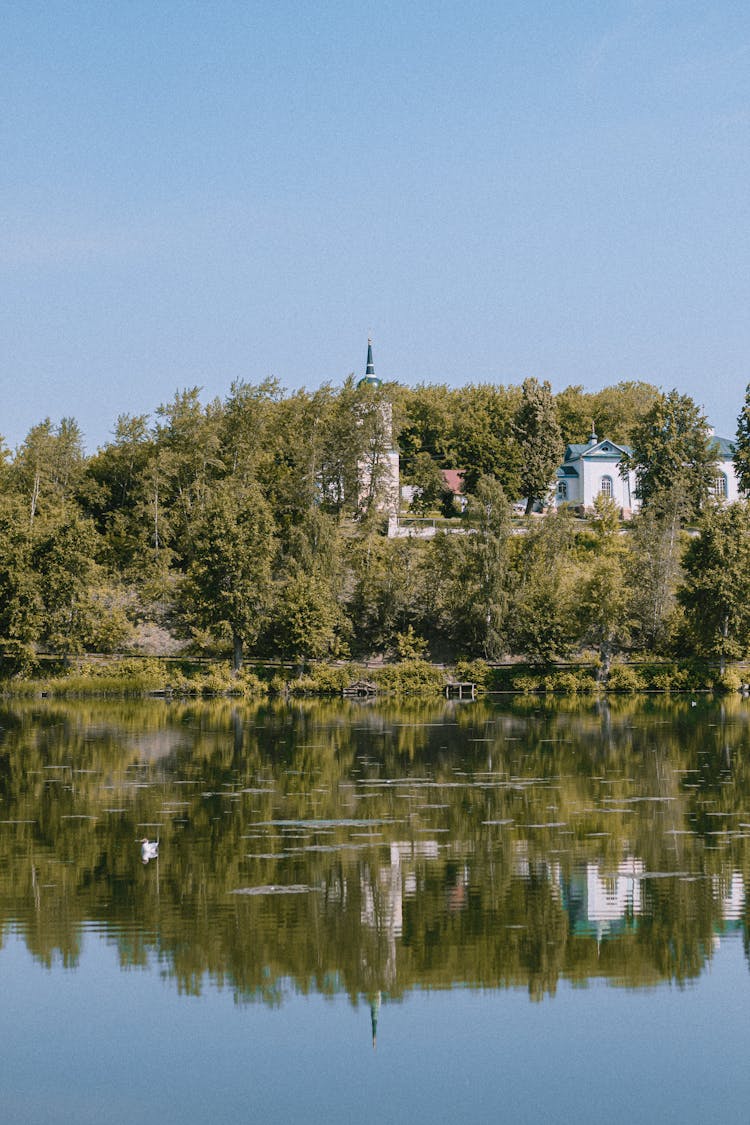 White Concrete Building Surrounded Green Trees And Body Of Water