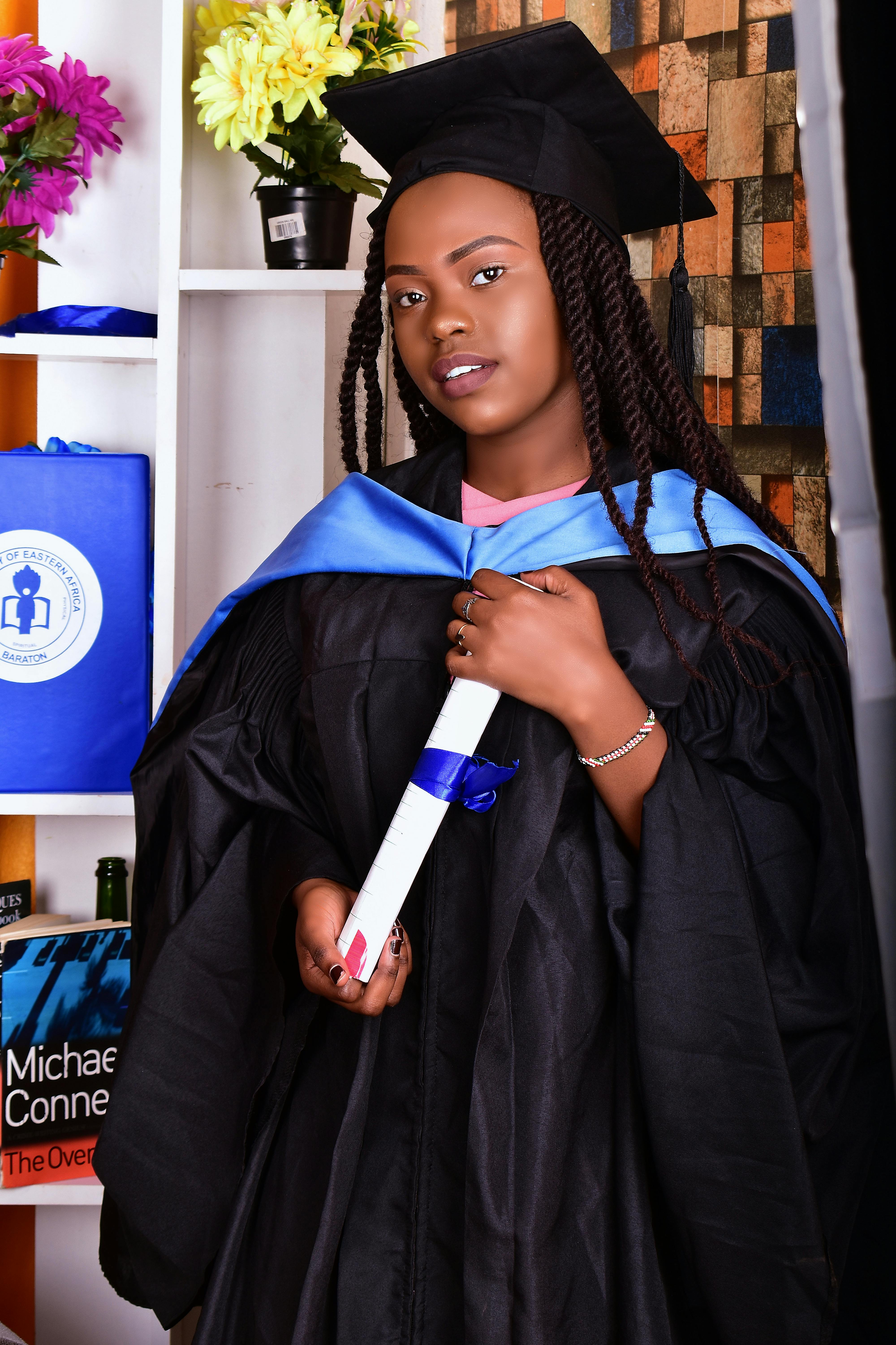 a woman in black academic regalia holding her diploma