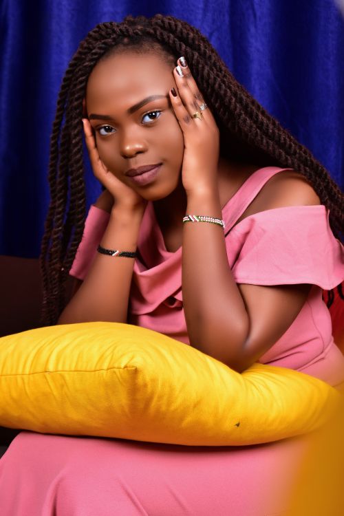 Free Beautiful woman in pink dress posing with a yellow pillow indoors. Stock Photo