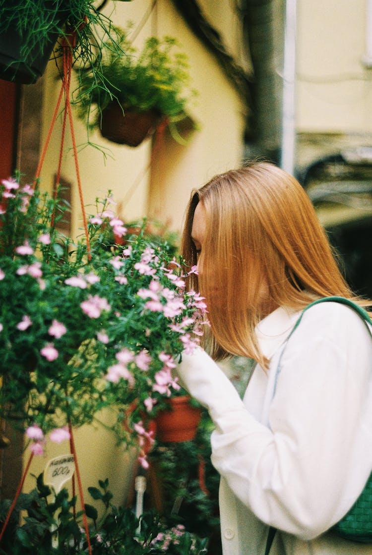 Redhead Woman Sniffing Flowers In Hanging Pots