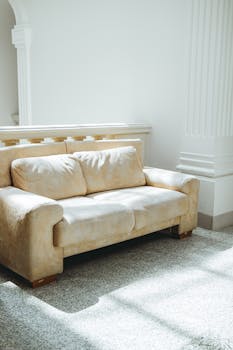 A luxurious beige sofa in a sunlit room with classic architectural details.