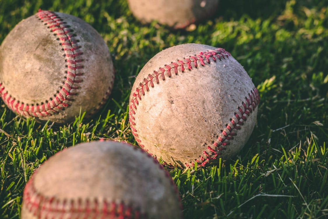 Close Up Photography of Four Baseballs on Green Lawn Grasses before I love you