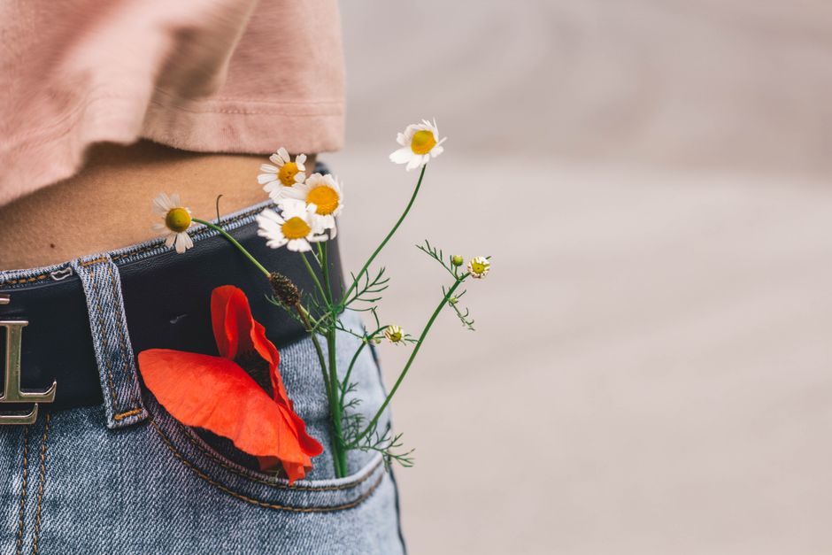 Close-up of wildflowers in a denim pocket, showcasing casual fashion and nature.