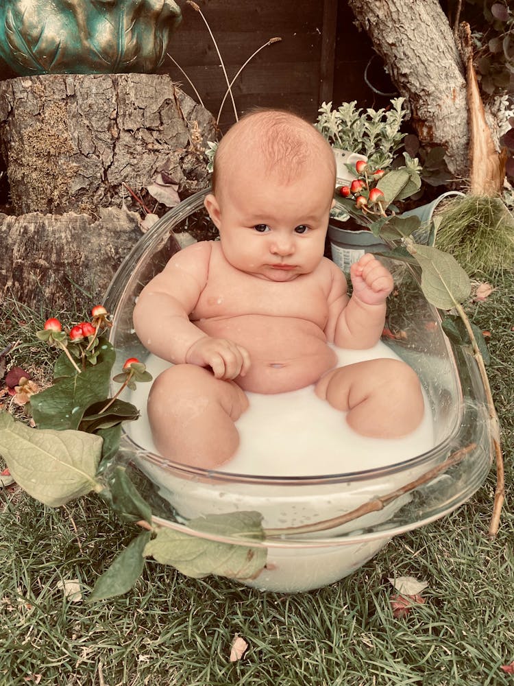 Baby Sitting In Glass Bathtub Filled With Milk