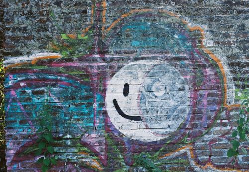 Free Vibrant street art with a smiley face on a textured brick wall adds urban charm. Stock Photo