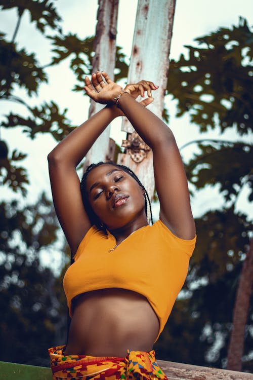 A Woman in Yellow Crop Top Raising Her Hands with Her Eyes Closed