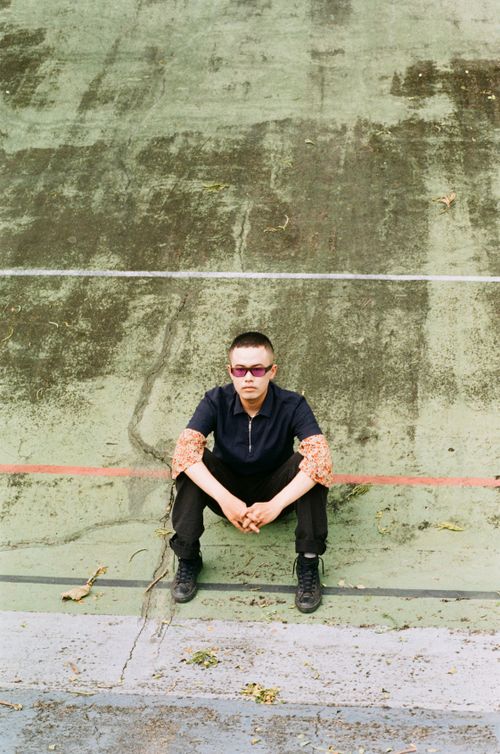 Free Man in sunglasses sitting on worn tennis court surface with leaves. Stock Photo