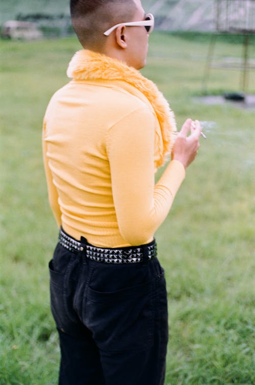 A Person in Yellow Long Sleeve Shirt Holding a Cigarette