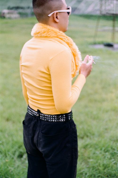 Free Person in bright yellow top with sunglasses smoking outdoors in vibrant setting. Stock Photo