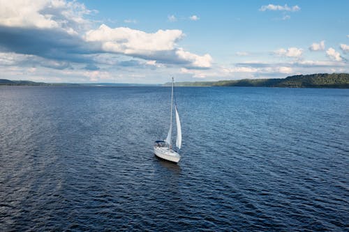 A Sailboat on Sea Under the Blue Sky and White Clouds