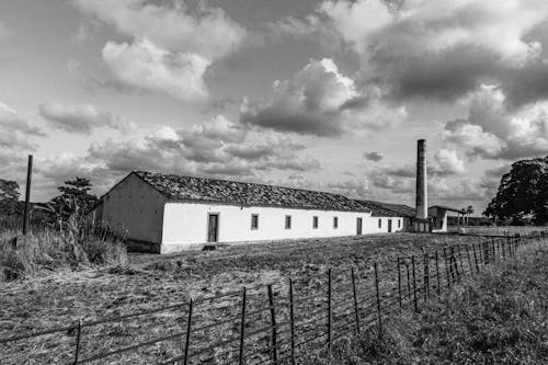 A Grayscale of a Building with an Industrial Chimney in the Countryside