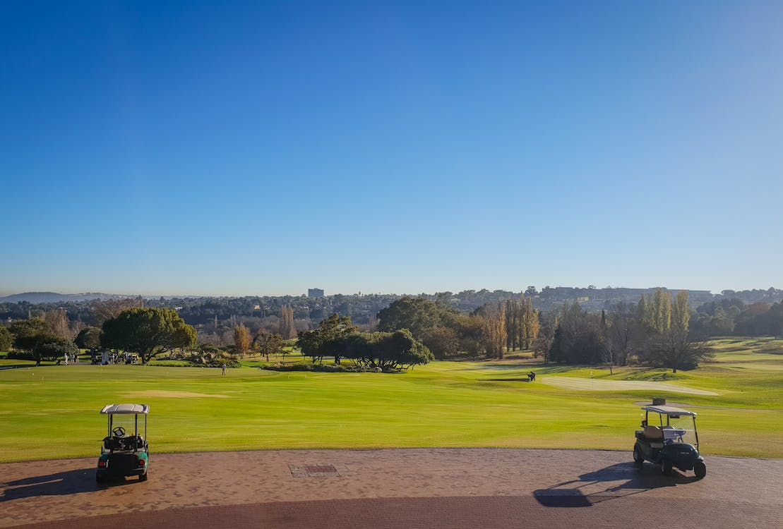 Two Golf Carts on Field Under Blue Sky