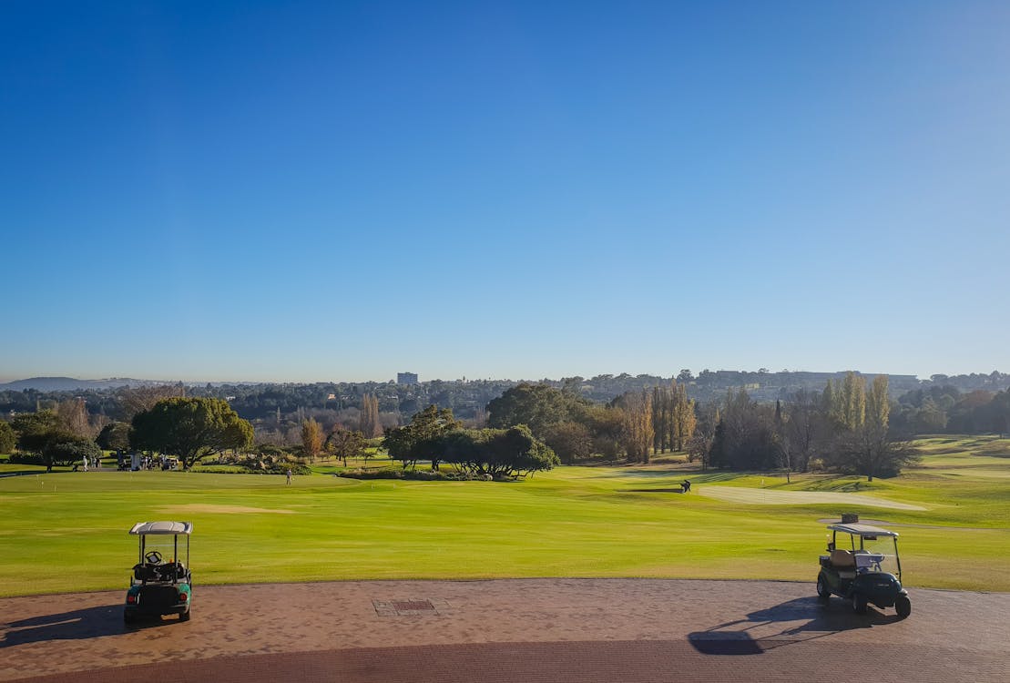 Free Two Golf Carts on Field Under Blue Sky Stock Photo