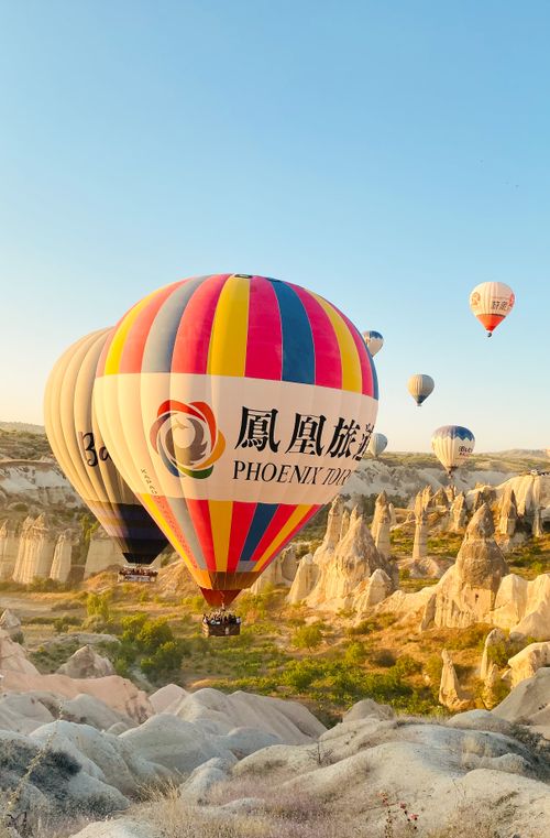 Free Colorful hot air balloons rise above Cappadocia's rock formations in Turkey. Stock Photo