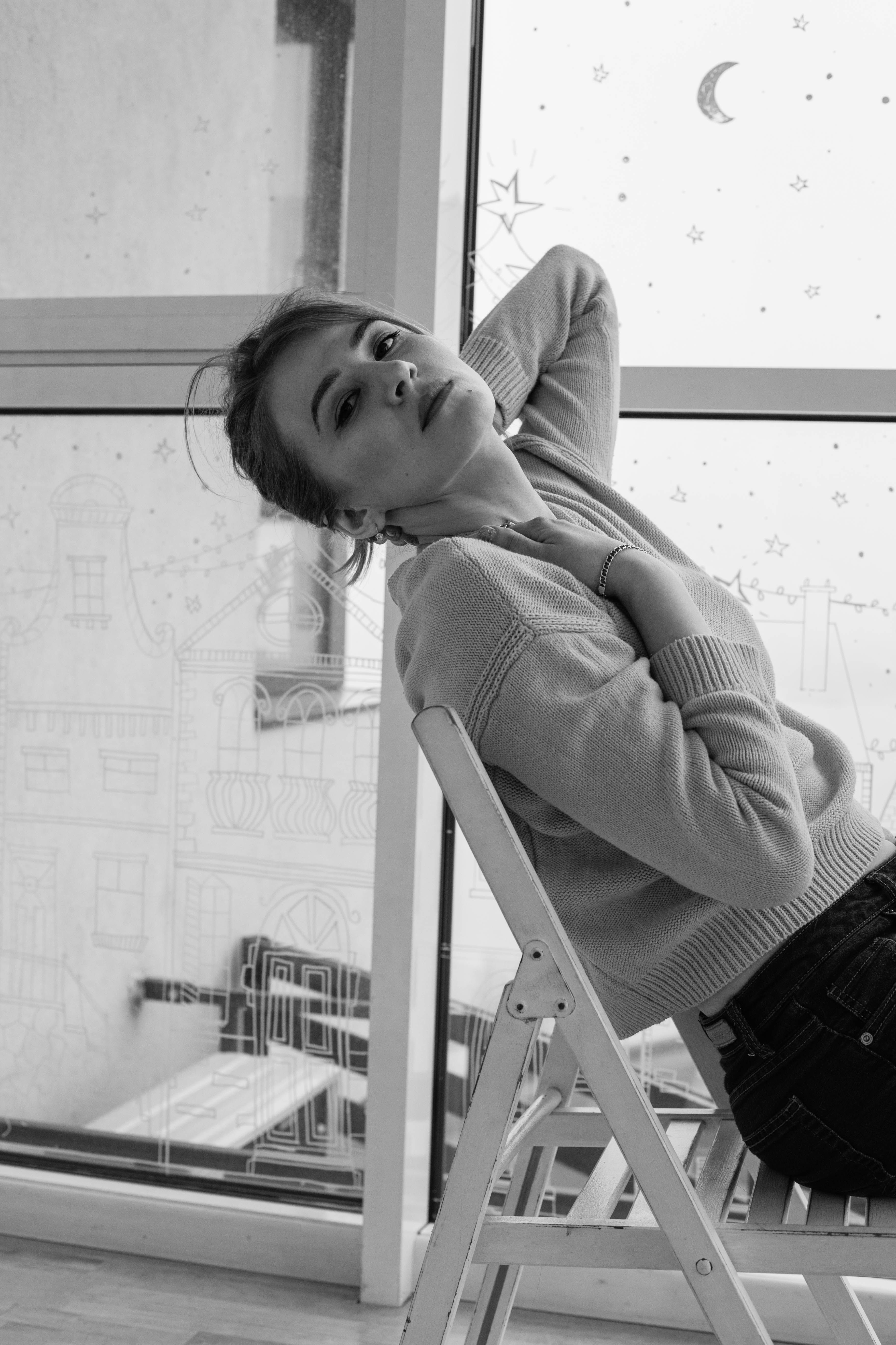 A Grayscale Photo of a Woman in Sweater Sitting on the Chair · Free ...