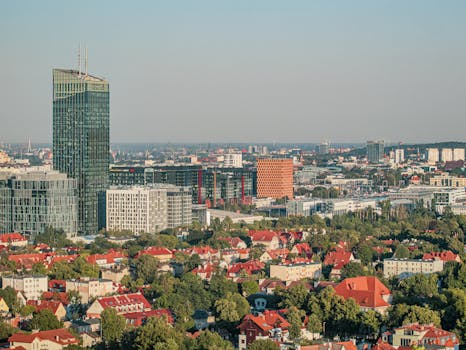 An aerial view of a modern urban skyline with residential and commercial buildings under a clear sky.