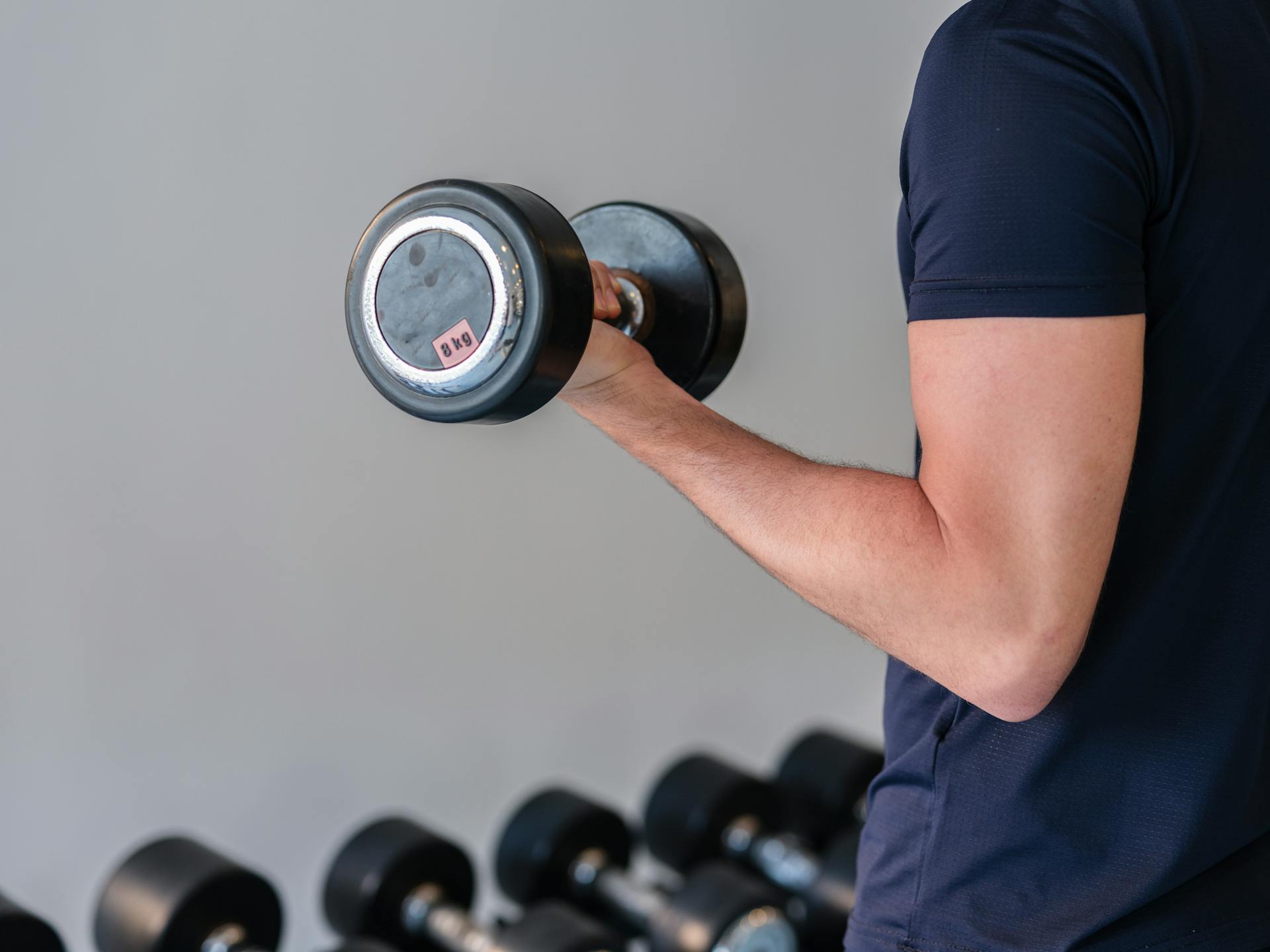 Close-up of a man lifting a dumbbell in a gym, emphasizing fitness and strength training.