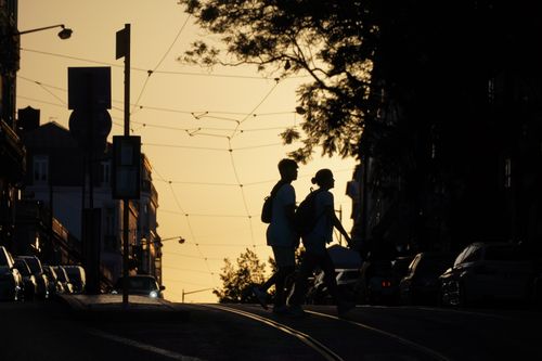 Free Silhouette of a couple crossing a city street at sunset, creating a dramatic urban scene. Stock Photo