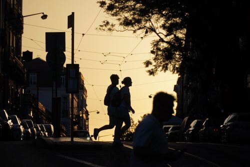 Free Silhouetted couple crossing a street at sunset, capturing urban life and golden hour ambiance. Stock Photo