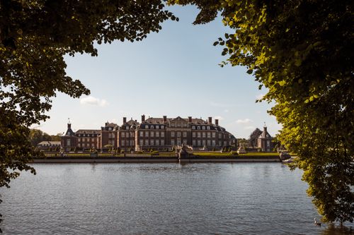 Free View of the majestic Nordkirchen Palace framed by lush trees, reflecting on a calm lake. Stock Photo