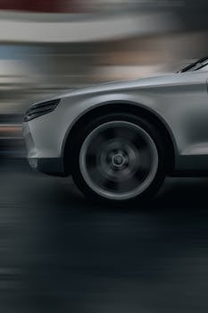 Dynamic shot of a silver car in motion, showcasing speed and sleek design on a city road.