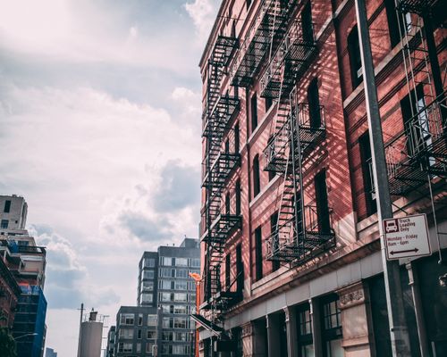 Free Low angle shot of a historic red brick building with fire escapes in a cityscape setting. Stock Photo