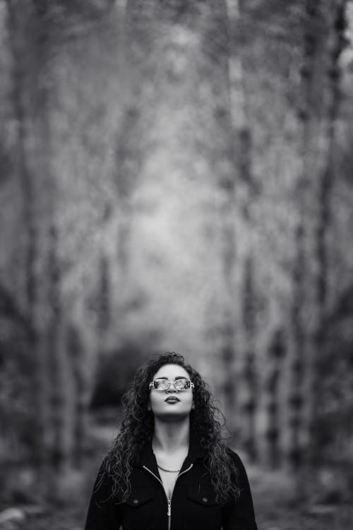 A Grayscale Photo of a Woman in Black Shirt Wearing Sunglasses while Looking Up