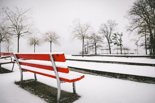 Free A vivid red bench covered in snow within a wintry park setting, evoking serene solitude. Stock Photo
