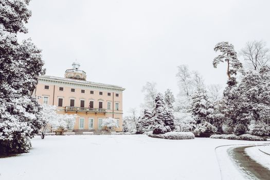 Serene winter scene with a snow-covered villa surrounded by trees.