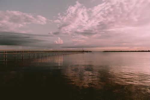 Free A tranquil sunset reflecting over the calm waters and pier at Igea Marina, Italy. Stock Photo
