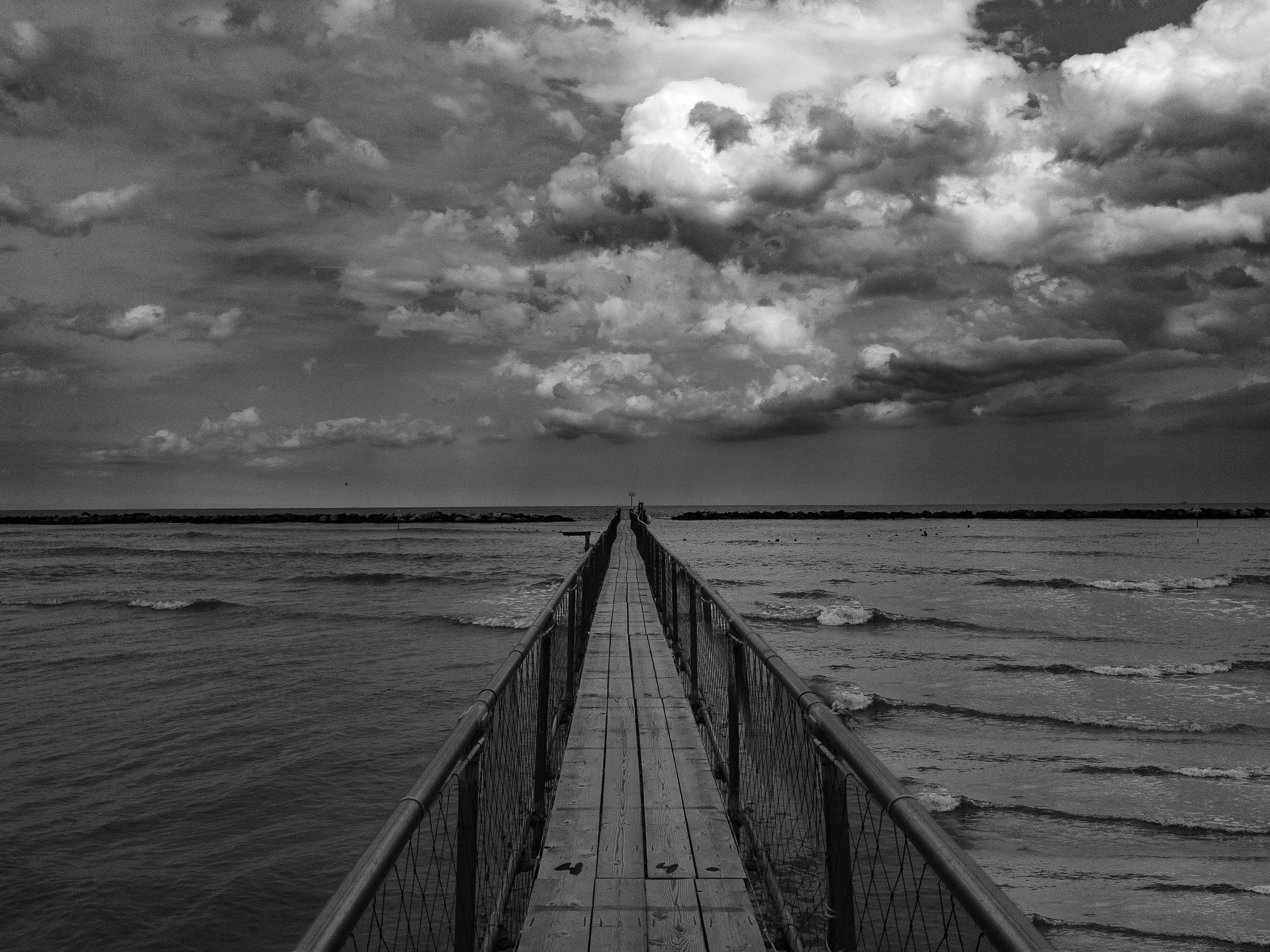 A Grayscale Photo of a Wooden Dock on the Sea Under the Cloudy Sky ...