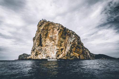 Free Dramatic cliff of Capo Caccia in Sardinia against a cloudy sky over the sea. Stock Photo