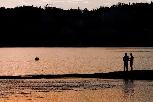 Two People Standing on the Beach during Sunset