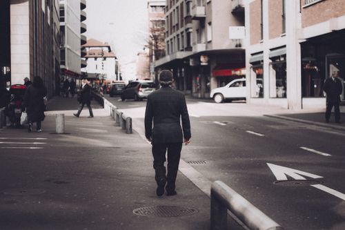 Free Man in black blazer strolls through a bustling Lugano street during the day. Stock Photo