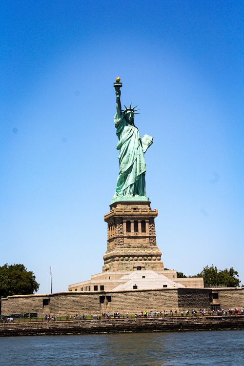 Free Iconic Statue of Liberty in New York with a clear blue sky, a symbol of freedom and democracy. Stock Photo