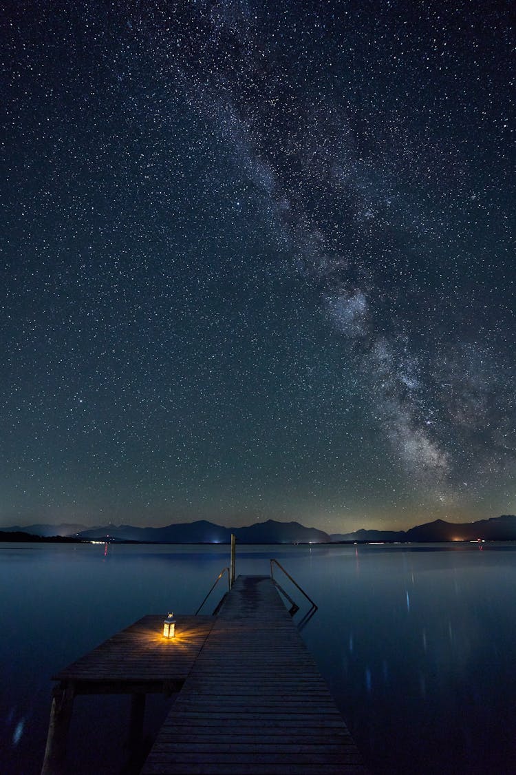 Light On Pier Near Water Under Starry Sky