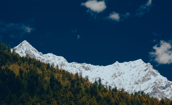 Breathtaking view of snow-covered Himalayan peaks against a deep blue sky in Manali, India.