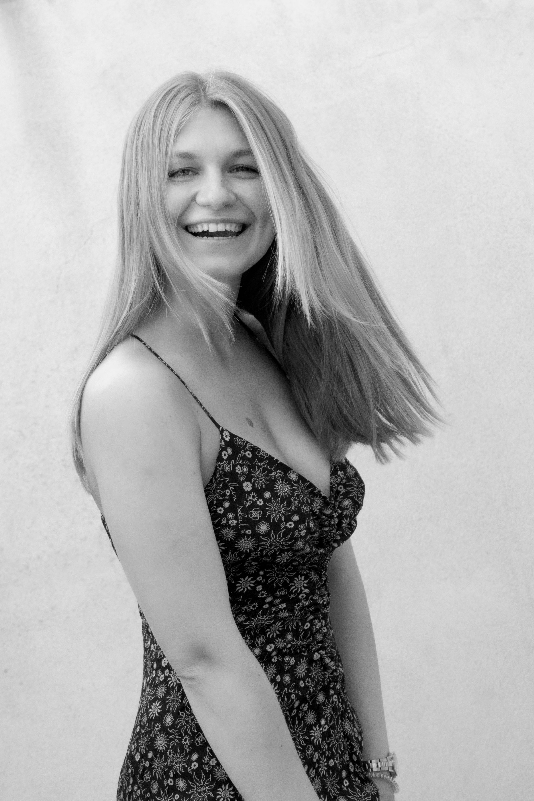 Elegant black and white portrait of a smiling woman in a floral dress.