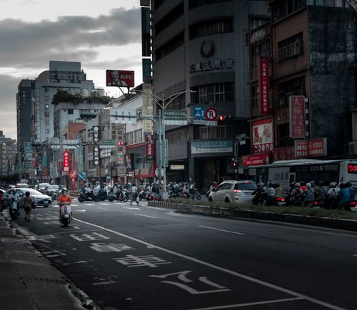 Free Crowded street in Taipei with traffic and scooters under a cloudy sky. Stock Photo
