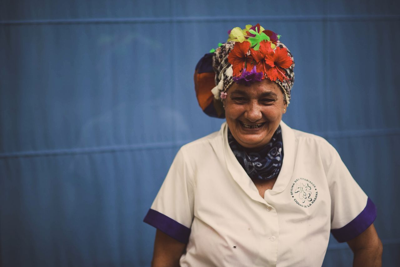 a joyous elderly woman wearing a colorful flower adorned headscarf enc