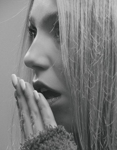 A Grayscale Photo of a Woman With Her Hand on Her Mouth