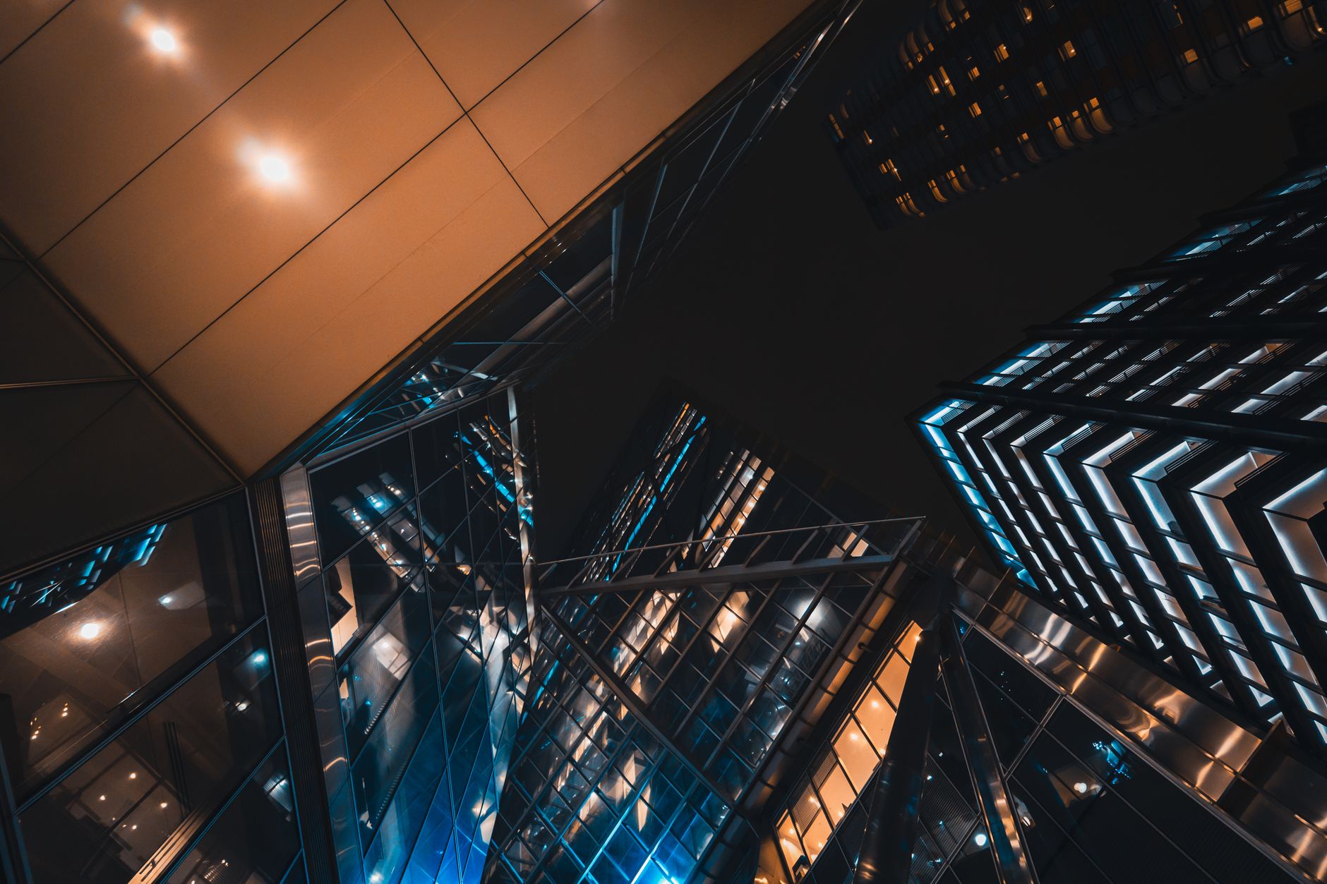 Dramatic low-angle view of modern skyscrapers in London illuminated at night. (Photo by Andrea De Santis on Pexels)
