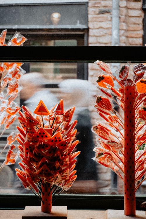 Free Colorful lollipop display inside a candy shop window with blurred pedestrians outside. Stock Photo