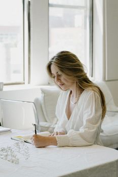 Blonde Attractive Woman Sitting at Table and Reading Book