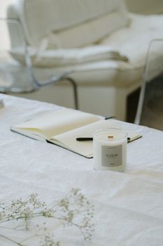 Candle Standing Next to Open Notebook on Table